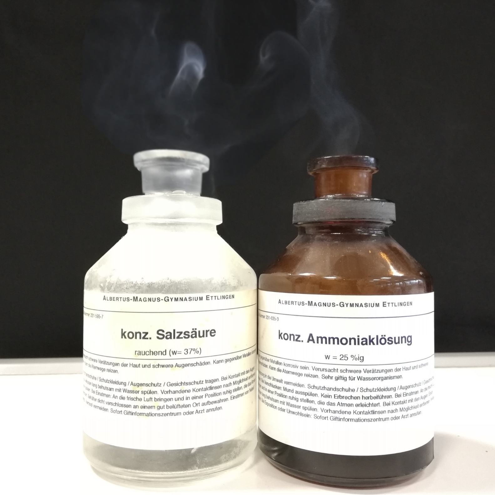 Bild aus dem Chemischen Fotokalender: Zwei geöffnete Glasflaschen, aus denen Rauch aufsteigt