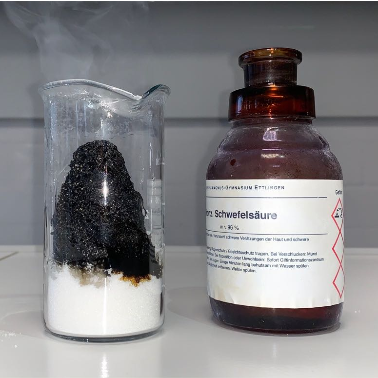 Bild aus dem Chemischen Fotokalender: Glasflasche und Glas mit dampfendem Feststoff