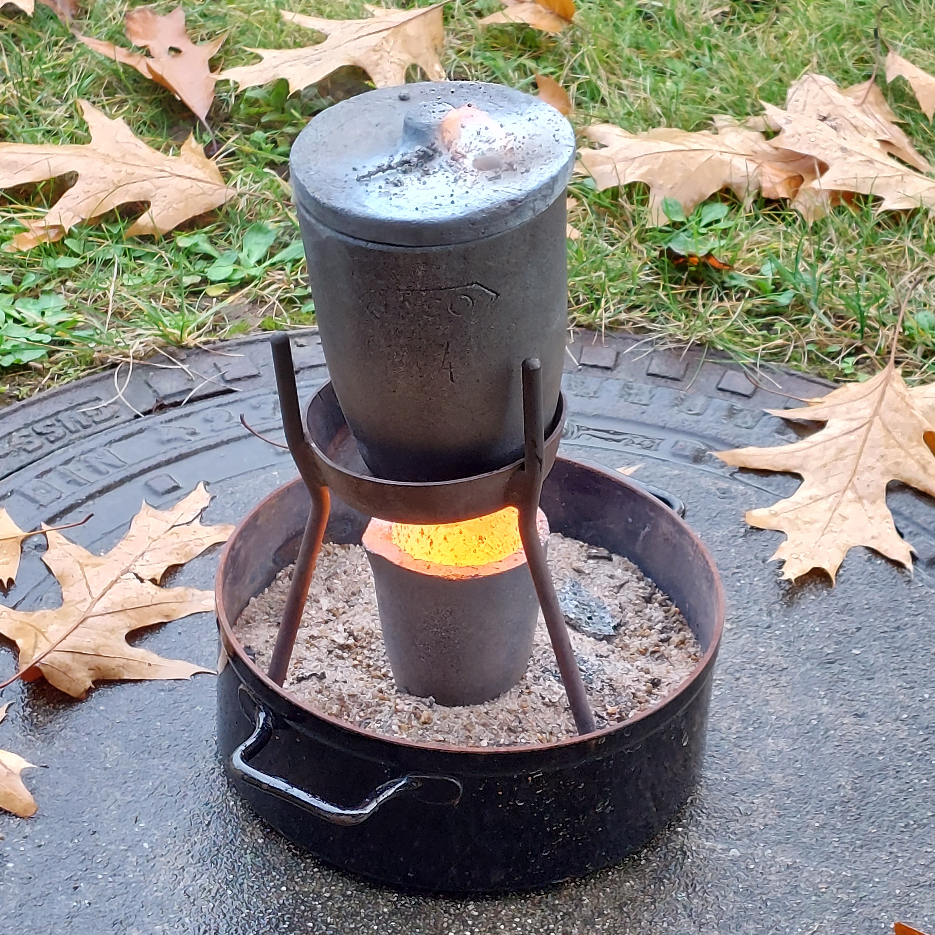 Bild aus dem Chemischen Fotokalender: Metallgefäß auf einem Dreibein in einem Topf mit Sand
