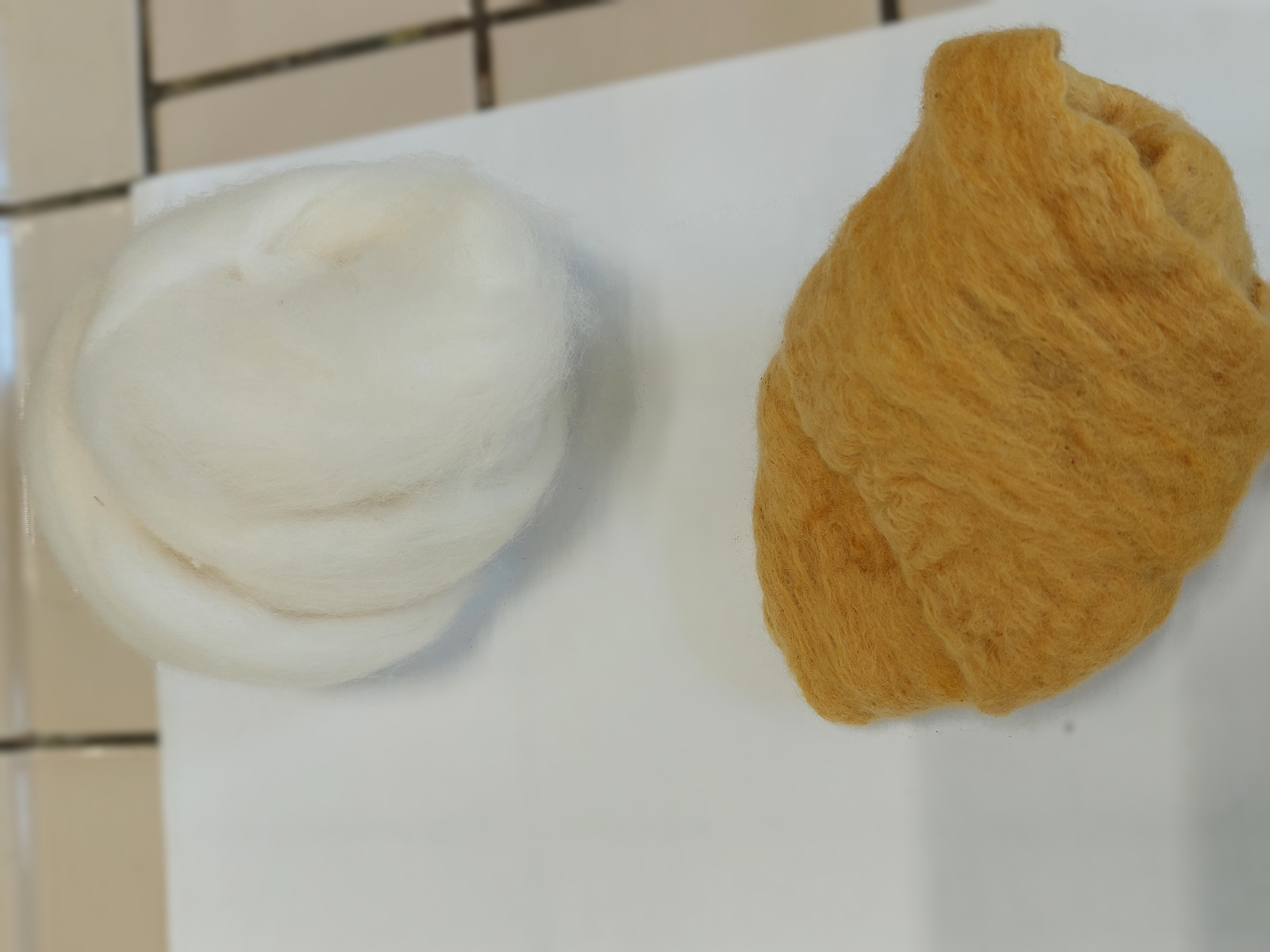 etwas weiße, ungefärbte Wolle neben etwas bräunlich-gelb gefärbter Wolle
