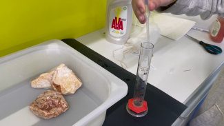 Flüssigkeit wird aus einer Pipette in einen Messzylinder geträufelt