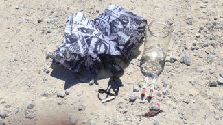 ein Regenschirm, ein leerer Glasbecher und zwei Thermometer in der Sonne